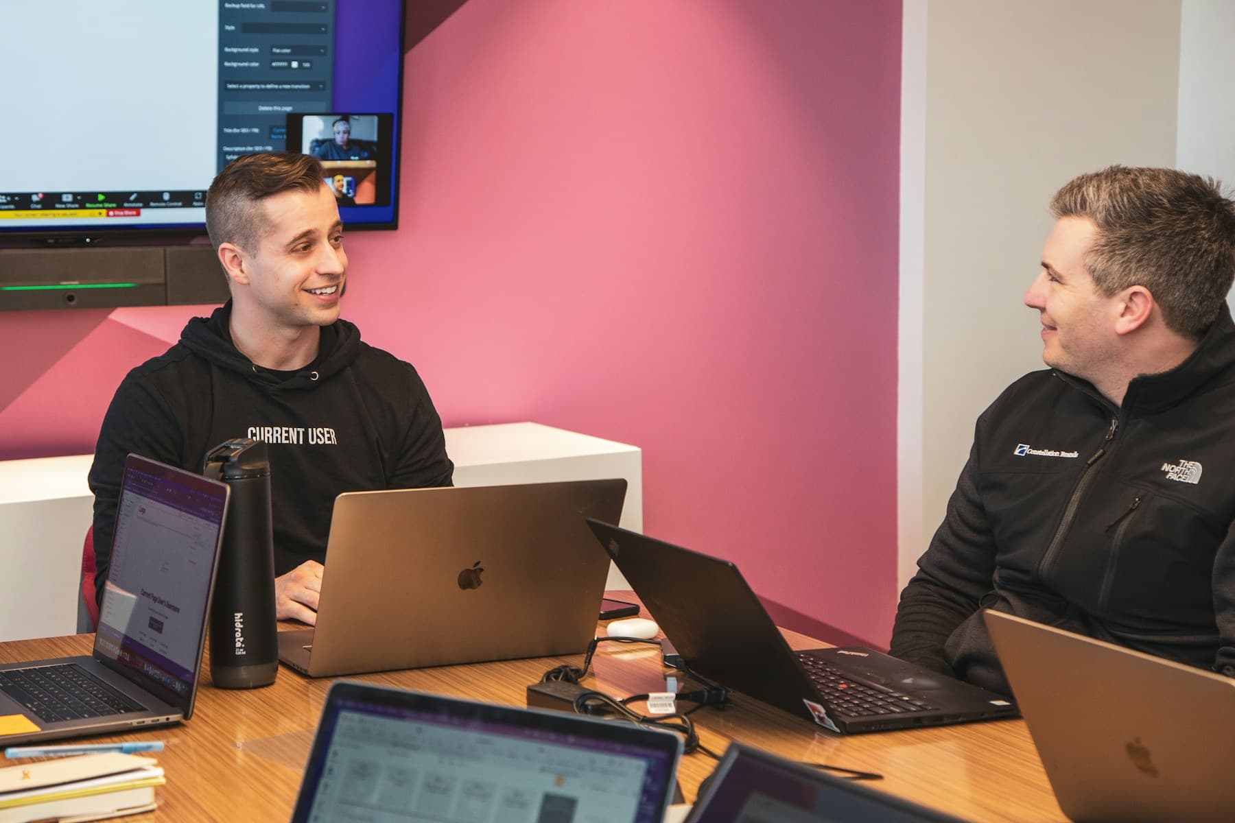 Developers discussing a project around a table with their laptops